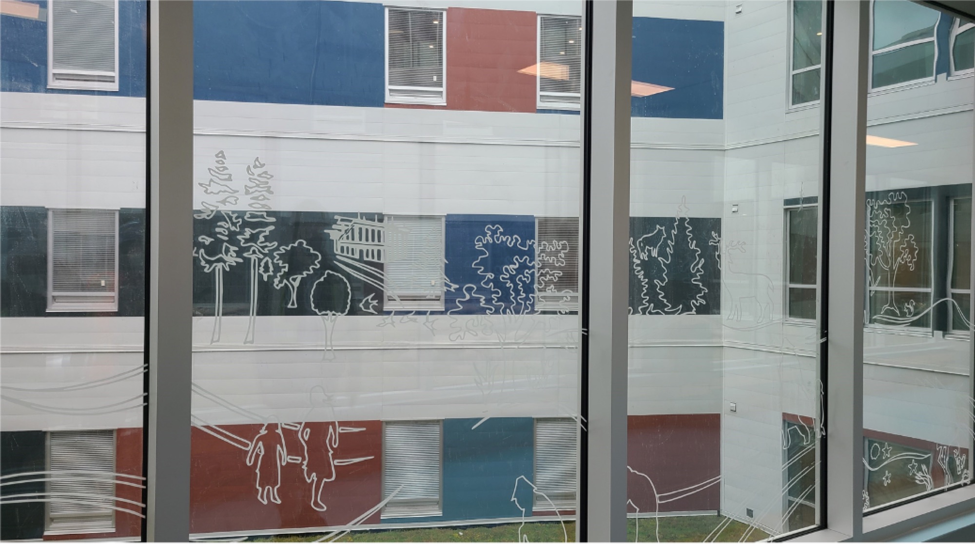 Figures, trees and a longhouse drawn on corridor glass